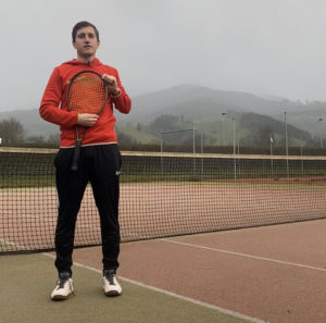 Tennistrainer Julian in Sportklamotten auf einem Tennisplatz.